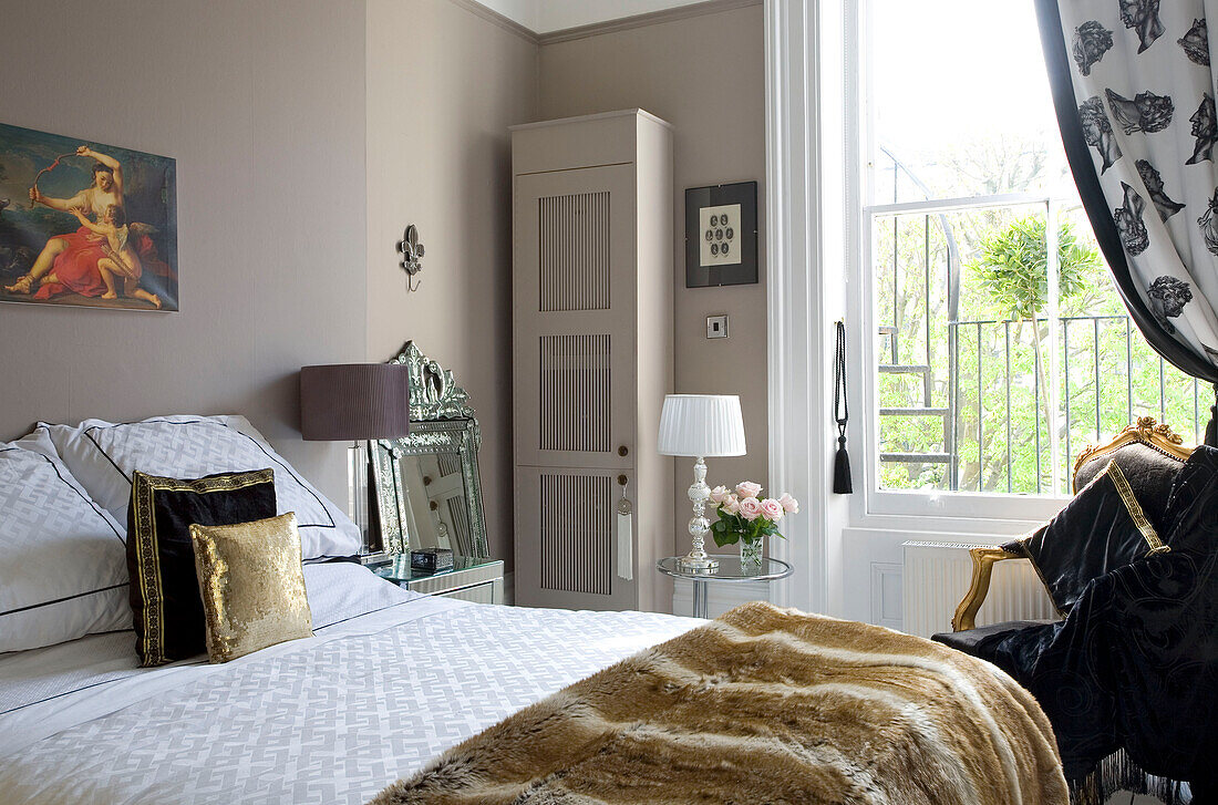 Gold cushions on bed with painted wardrobe in Hove home East Sussex UK