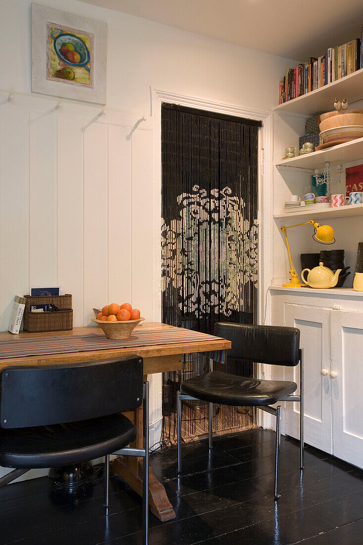 Black leather chairs at table in kitchen of London home UK