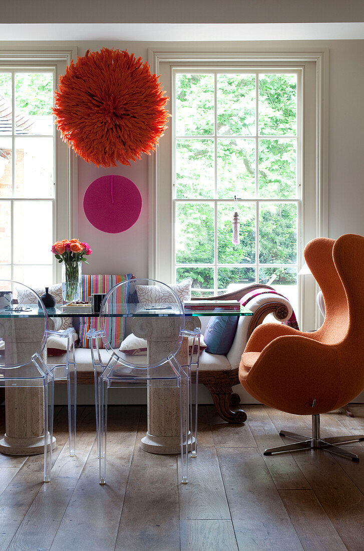 Glass topped dining table and Ghost chairs at sash windows in dining room