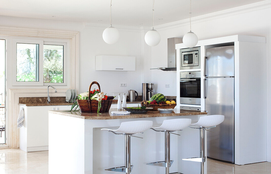 Pendant lights and upright fridge in white kitchen of luxury holiday villa, Republic of Turkey