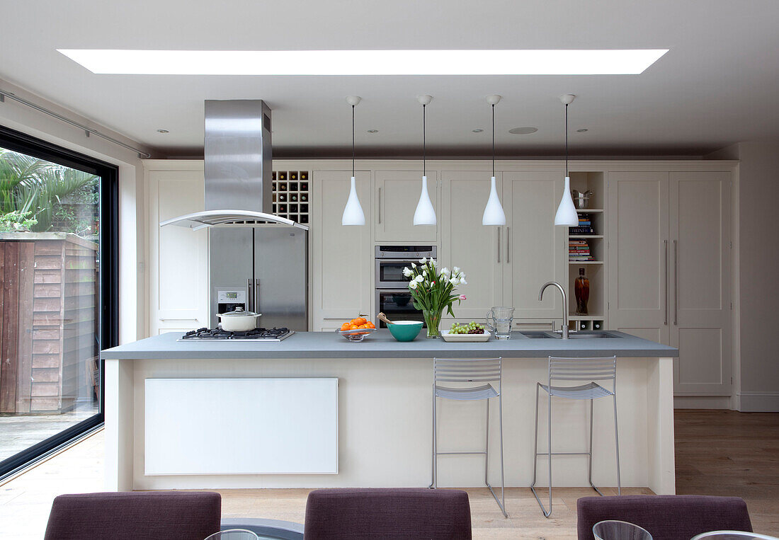Breakfast bar with pendant lights and extractor in London kitchen extension, UK