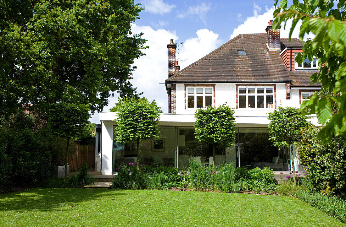 Mit Rasen bewachsener Garten hinter dem Anbau eines Wintergartens, Doppelhaushälfte in London, England, Vereinigtes Königreich