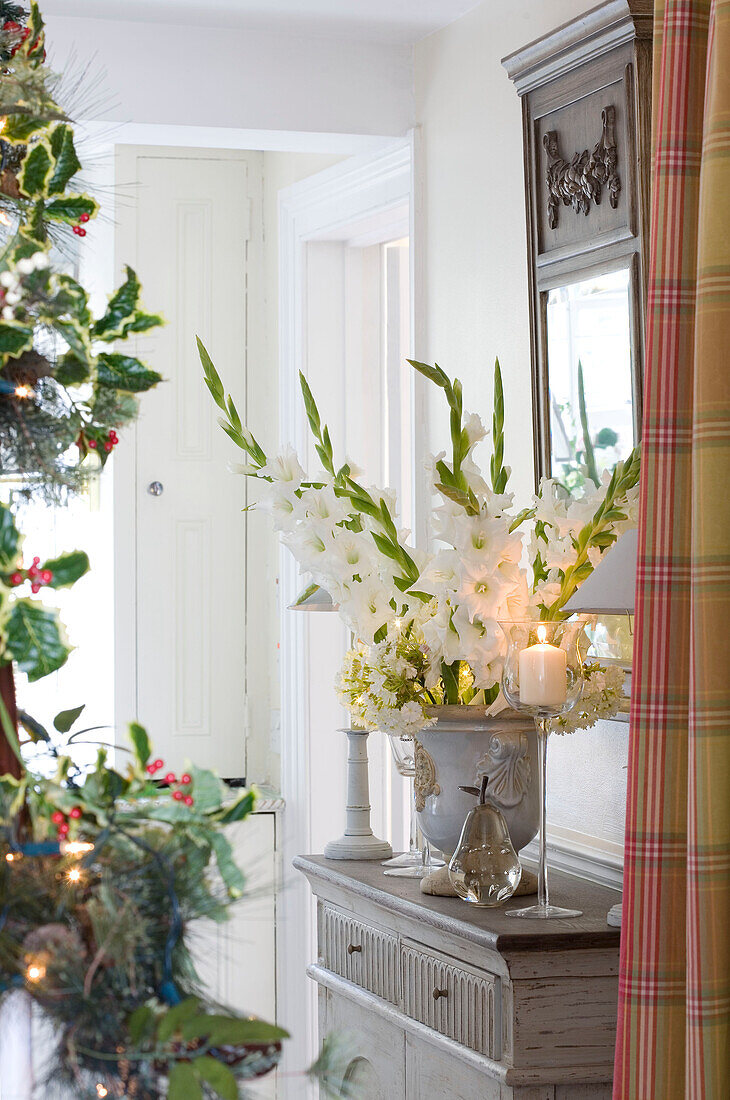 Lit candles and cut flowers on sideboard of London home UK