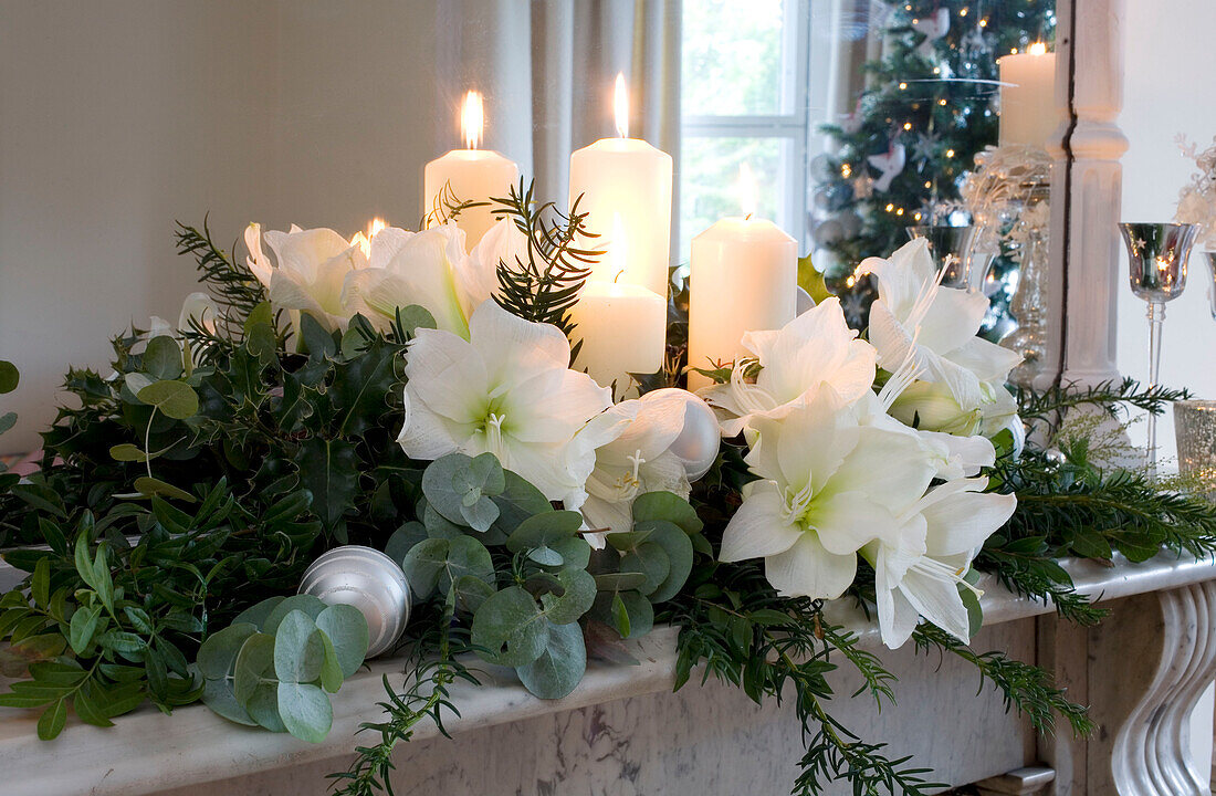 Lit candle and Christmas flower garland on marble mantlepiece of London home UK