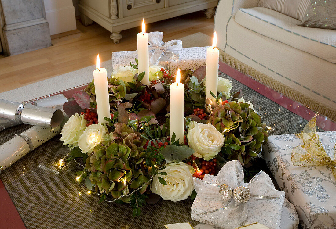 Beleuchtete Kerzen und Weihnachtskranz auf dem Couchtisch im Wohnzimmer eines Londoner Hauses, UK