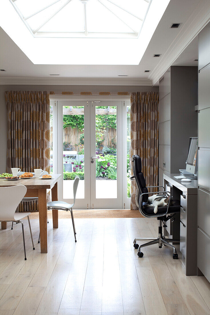 Office chair at desk and table in open plan extension of contemporary London home, UK