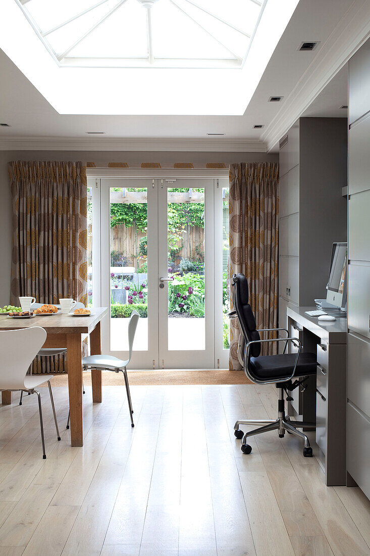 Office chair at desk and table in open plan extension of contemporary London home, UK