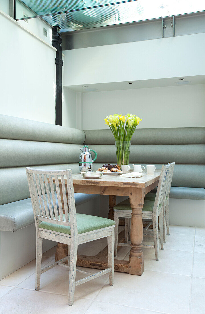 Wooden table with bench seat and chairs in basement conversion of contemporary London townhouse, UK