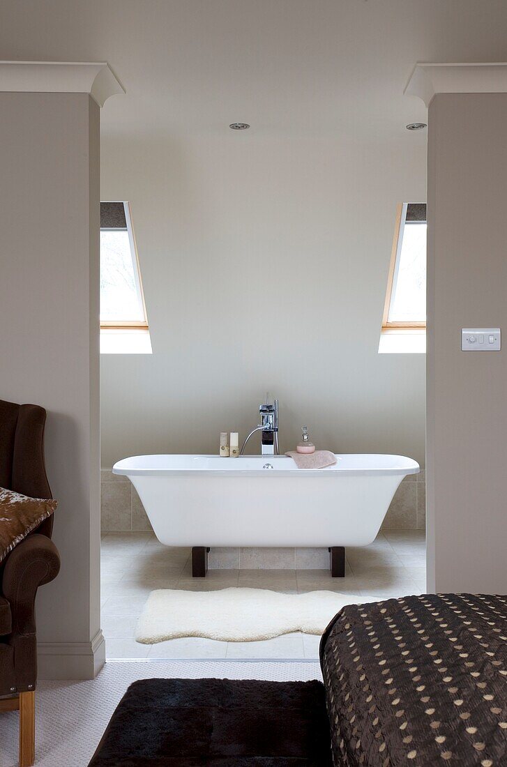 View through wall partition to freestanding ensuite bath in contemporary London townhouse, UK