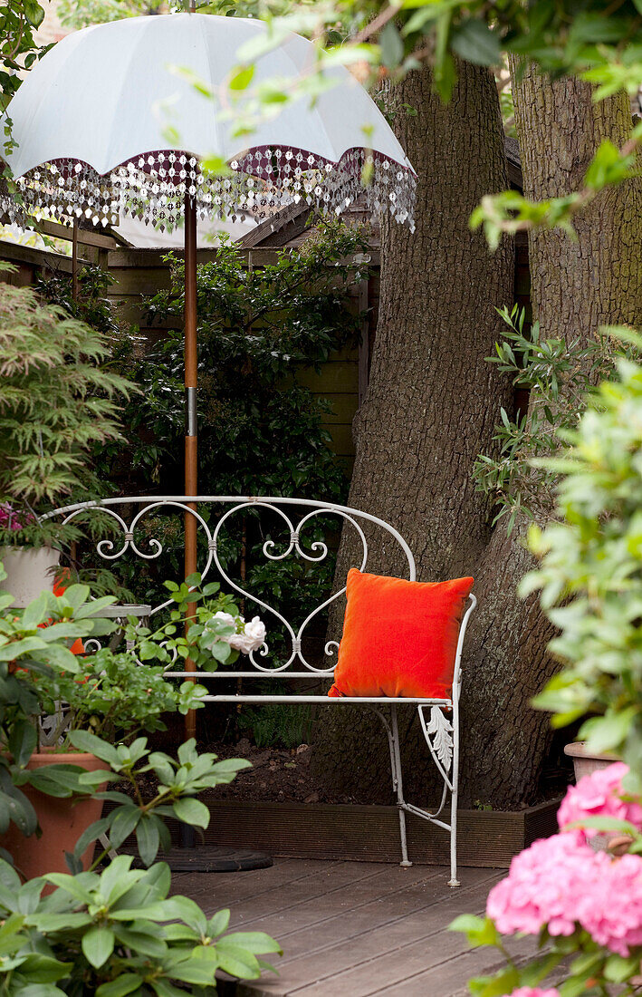 Sonnenschirm mit Metallbank im hinteren Garten eines Hauses in London, UK
