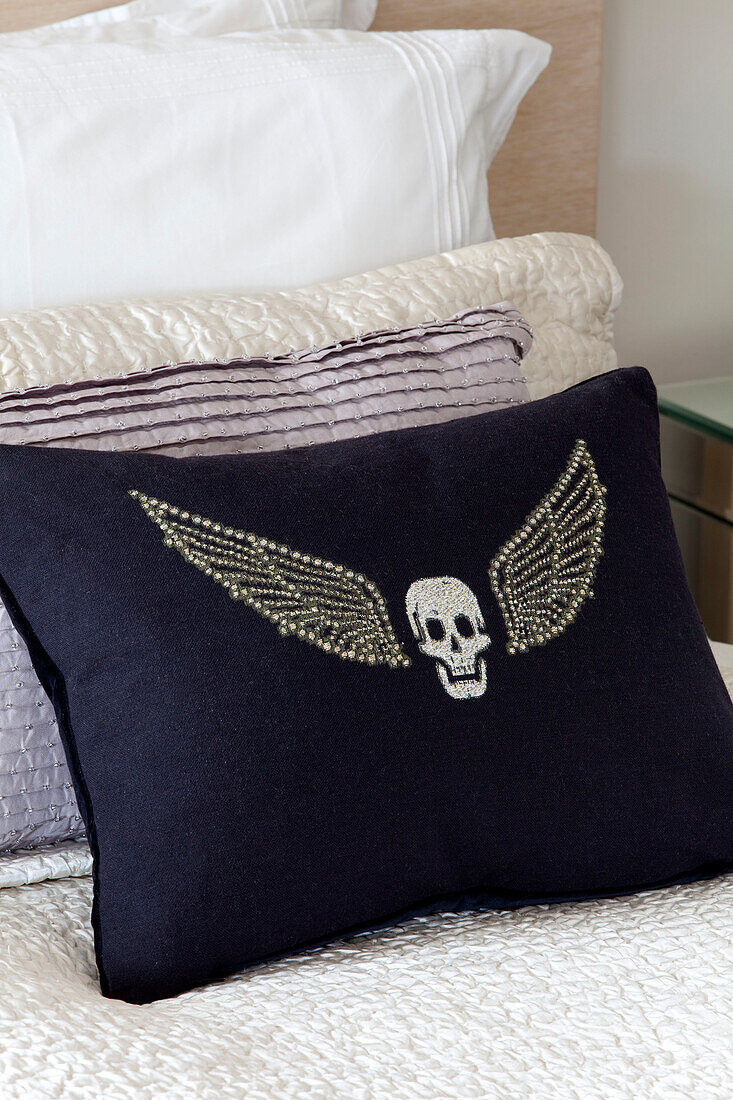 Winged skull on navy blue cushion in contemporary London home, UK