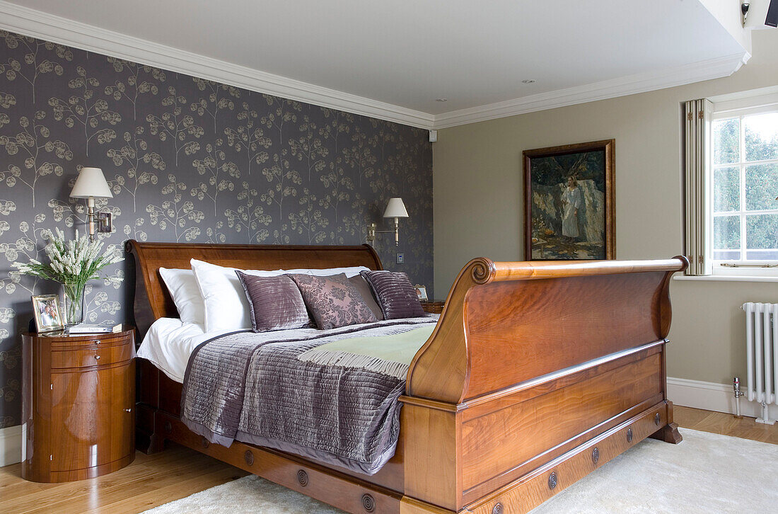 Nature inspired wallpaper and polished wooden antique bed in Surrey home UK