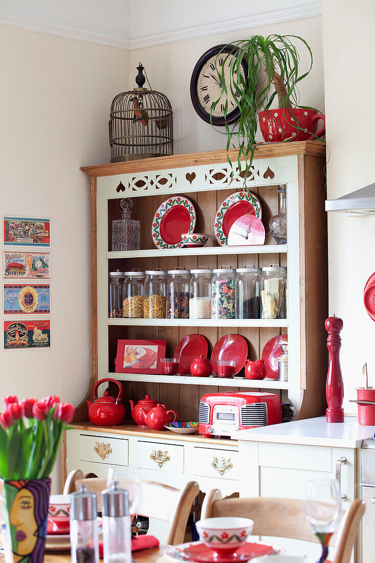 Vogelkäfig auf der Küchenkommode mit rotem Geschirr und Vorratsgläsern in einem Londoner Stadthaus, England, UK