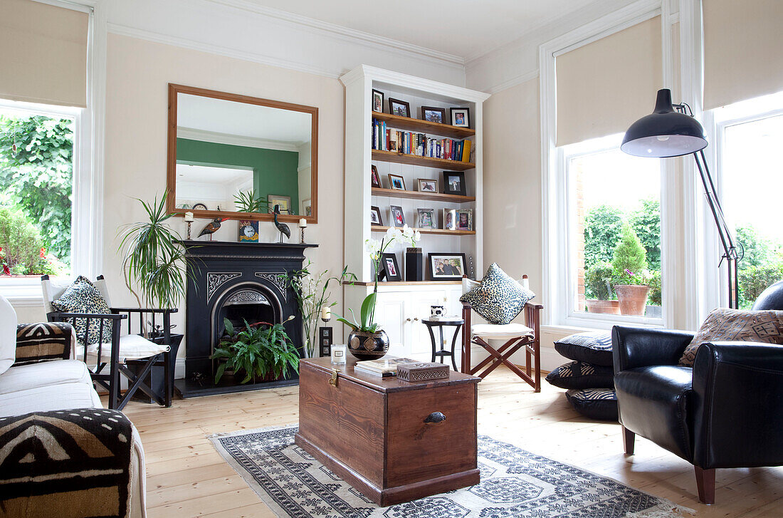 Wooden blanket box on rug in front of original fireplace in living room with wooden floorboards in London townhouse, England, UK