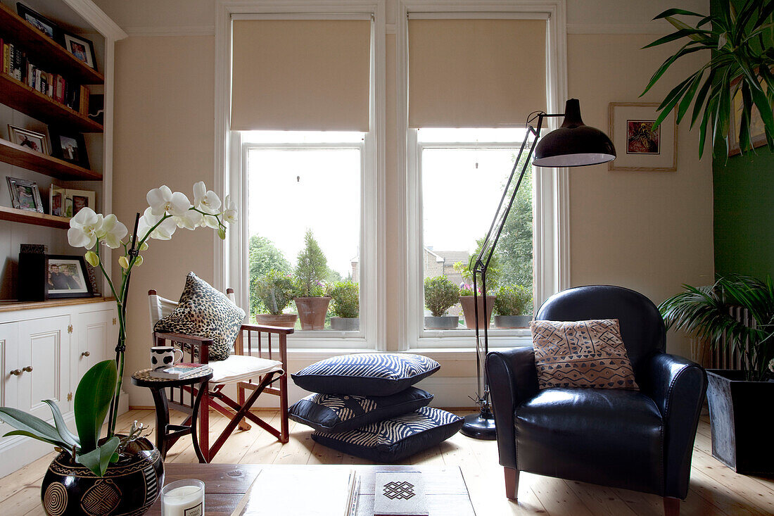 Black leather armchair and oversized anglepoise floor lamp in living room with sash windows in London townhouse, England, UK