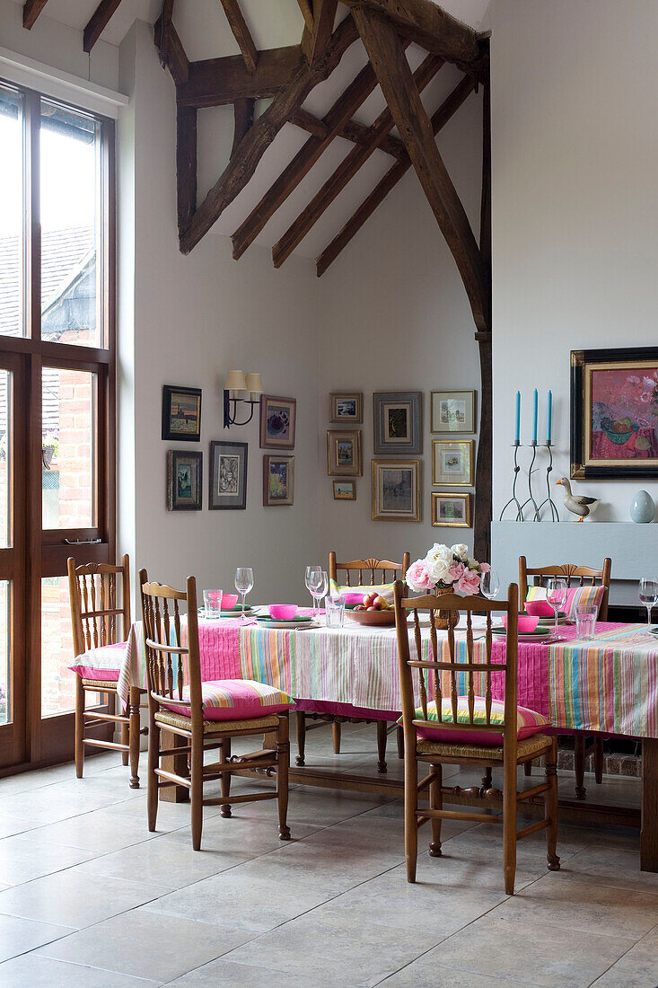 Artwork above fireplace in Sussex dining room with pink striped tablecloth