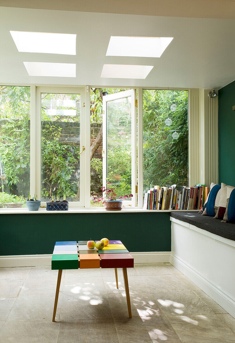 Conservatory extension with books on sill below open window in London home, England, UK