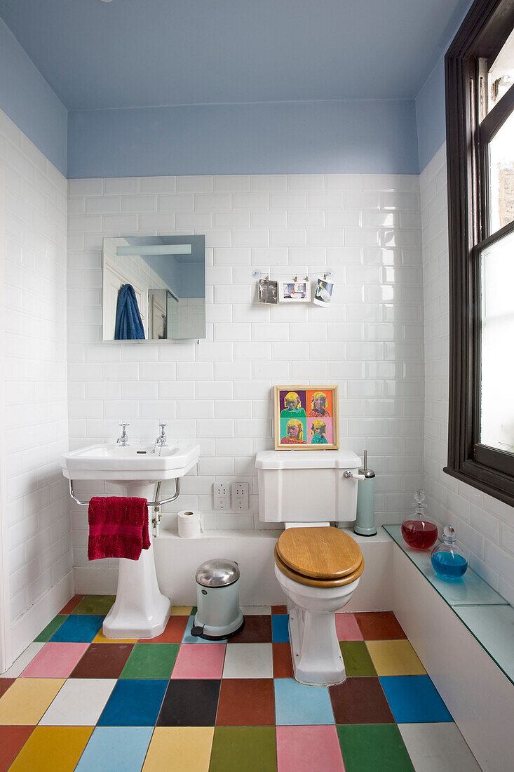 Multicoloured floor in white tiled bathroom of London home, England, UK