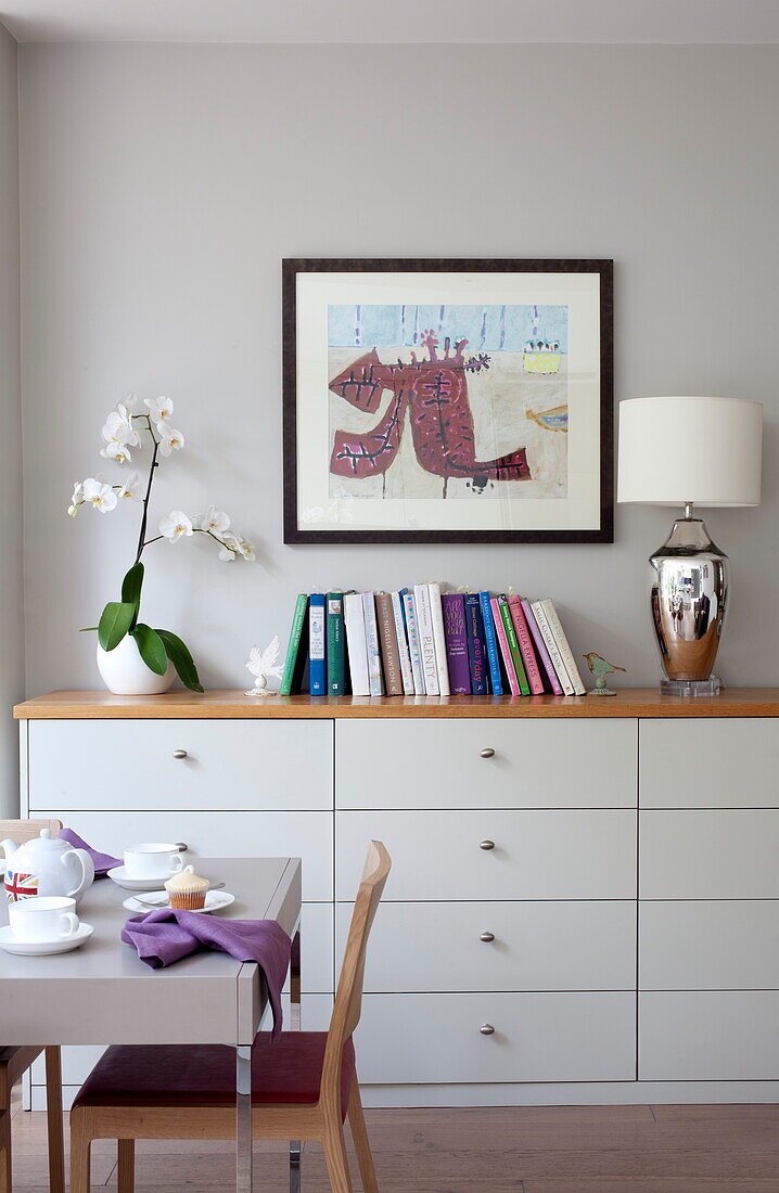 Sideboard with books and artwork in dining room of contemporary London townhouse, England, UK