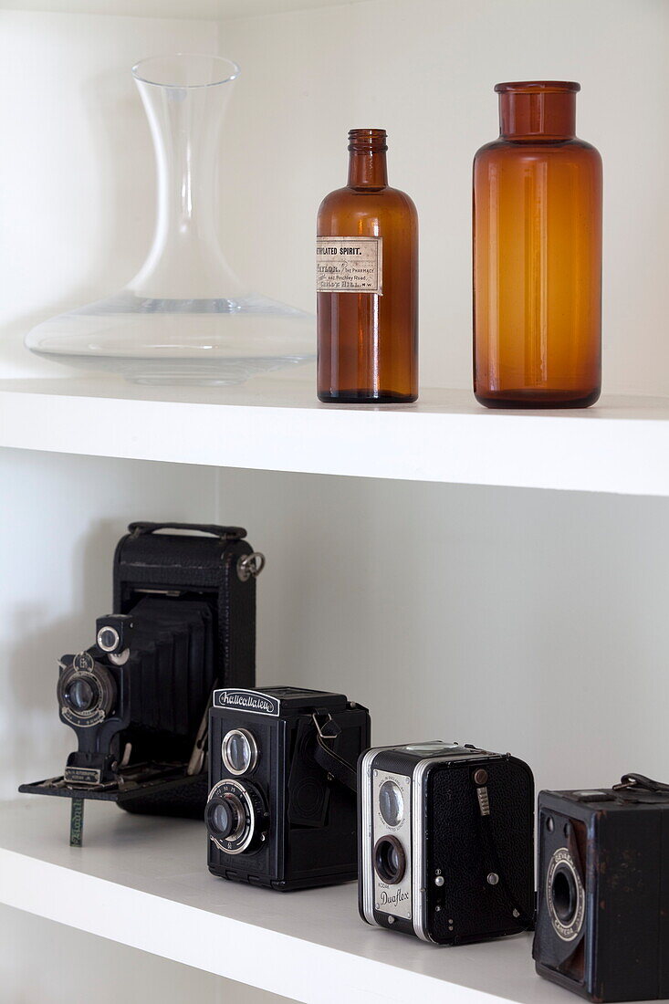 Vintage cameras and bottles on shelf in London townhouse, England, UK
