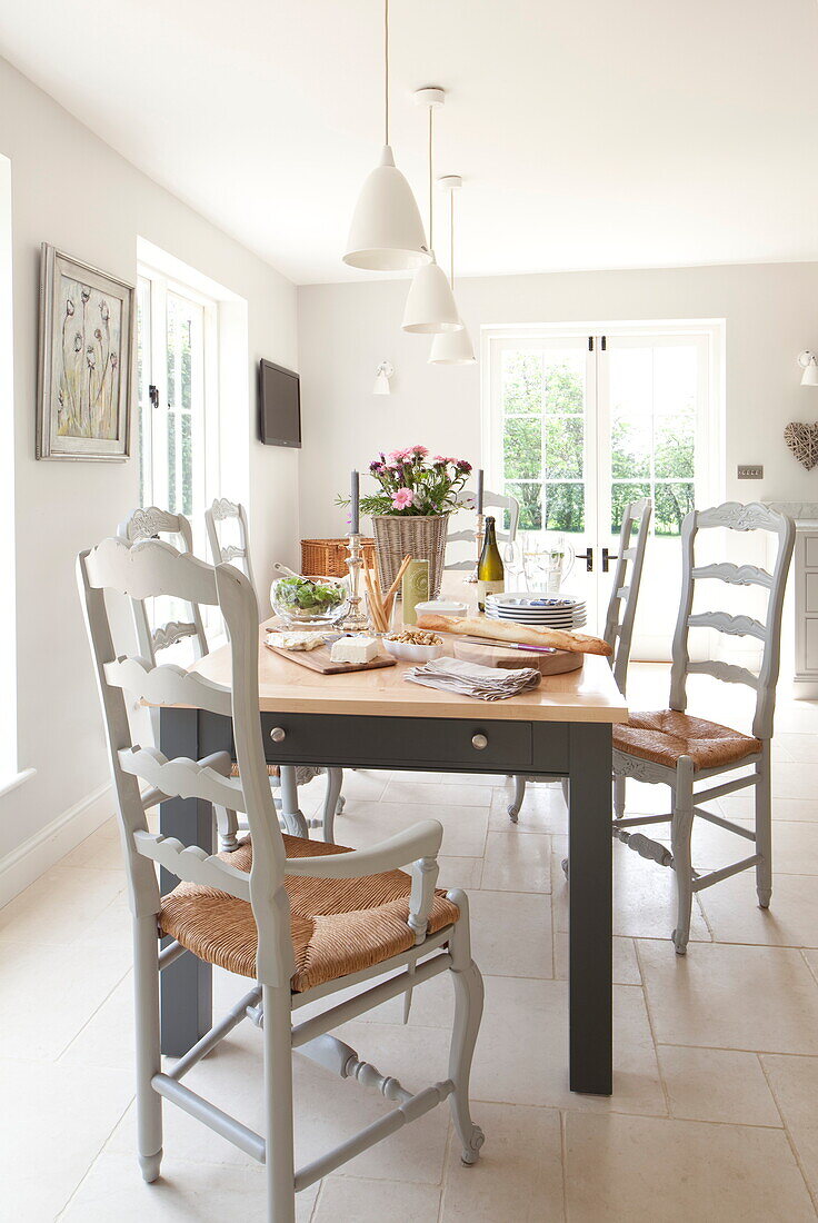 Dining table with wicker seated chairs in contemporary Maidstone farmhouse, Kent, England, UK