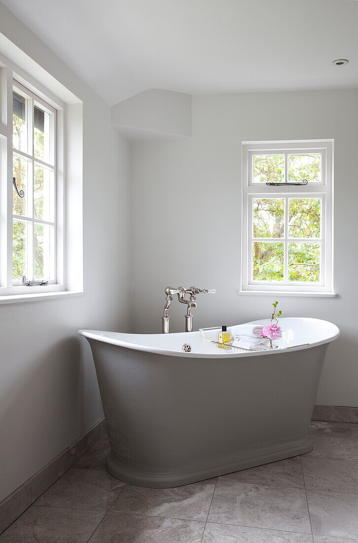 Freestanding bath below windows in corner of room, Maidstone farmhouse, Kent, England, UK
