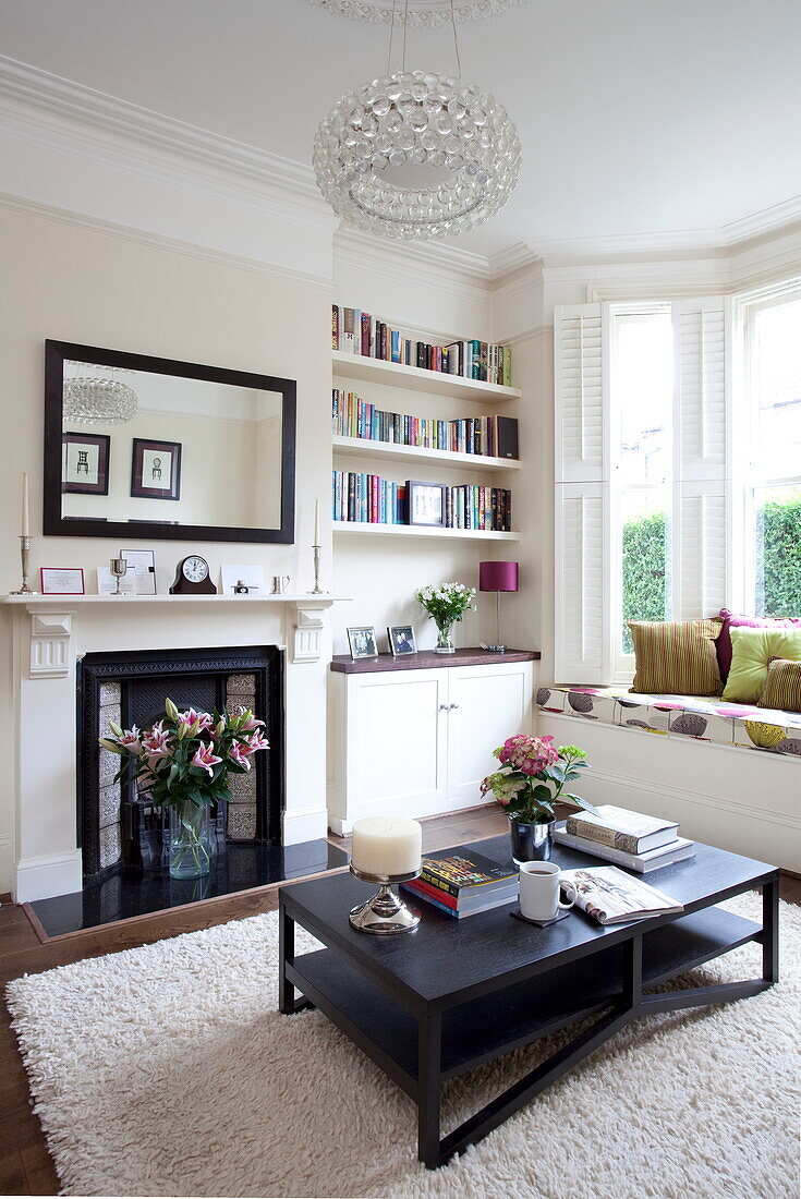 Glass ceiling light above coffee table wit Victorian fireplace in living room of London townhouse, England, UK