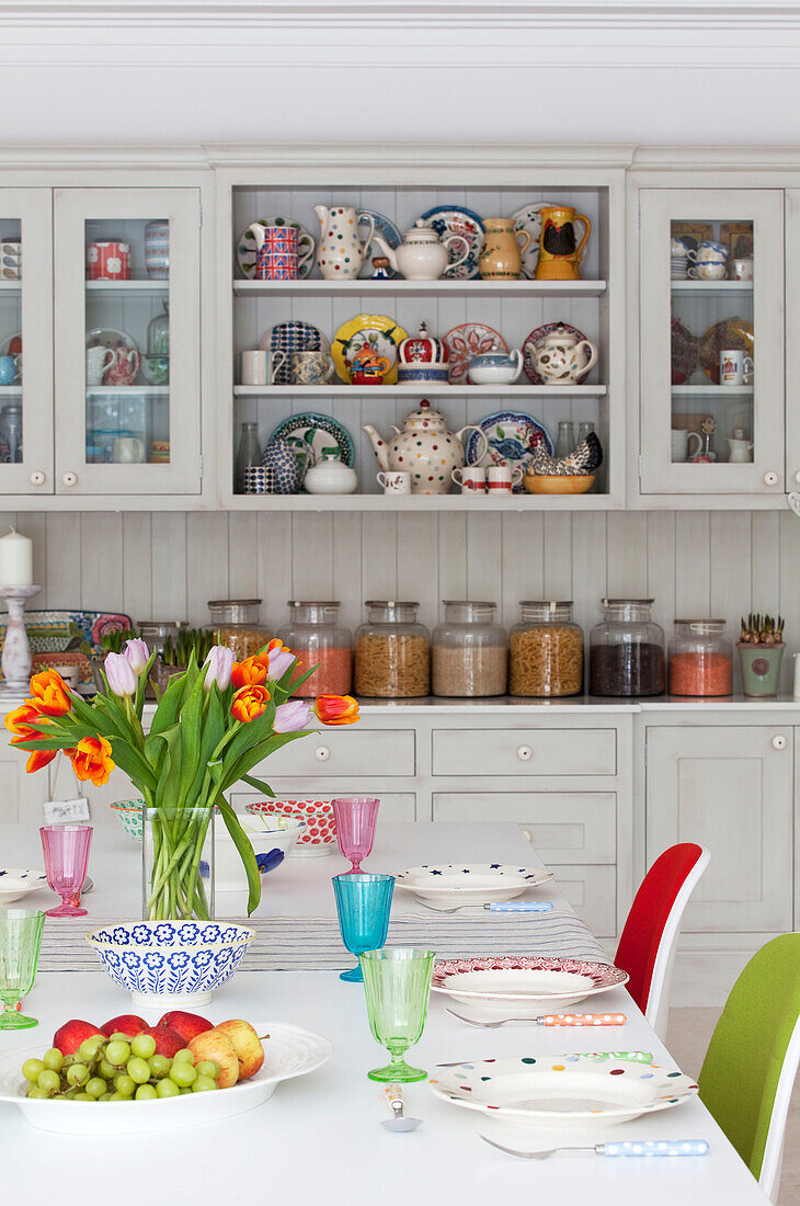 Cut tulips and place settings on table with kitchen storage in Surrey country home England UK