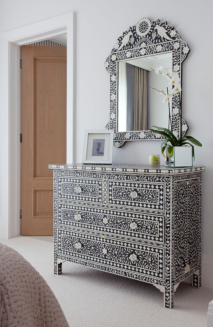 Kommode mit Intarsien und Spiegelrahmen im Schlafzimmer eines zeitgenössischen Landhauses in Surrey England UK