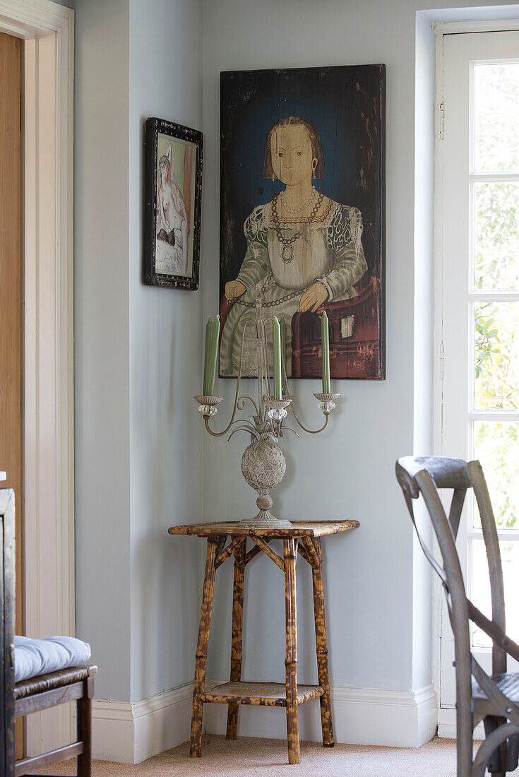 Historic artwork above side table with candlestick in Sussex home, England, UK