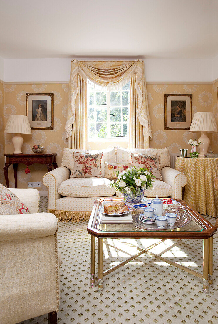 Teeservice auf einem gläsernen Couchtisch im sonnenbeschienenen Wohnzimmer eines Bauernhauses in Sussex, England, UK