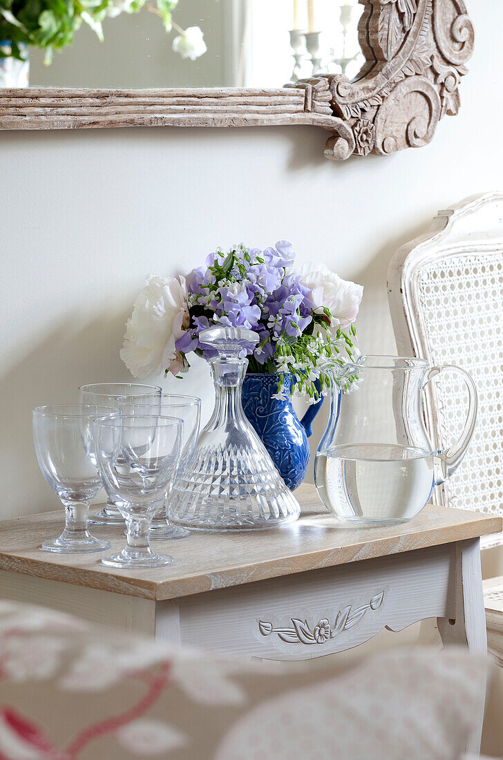 Krug mit Wasser und Gläsern auf Beistelltisch mit Schnittblumen in Cottage in Sussex, England, UK