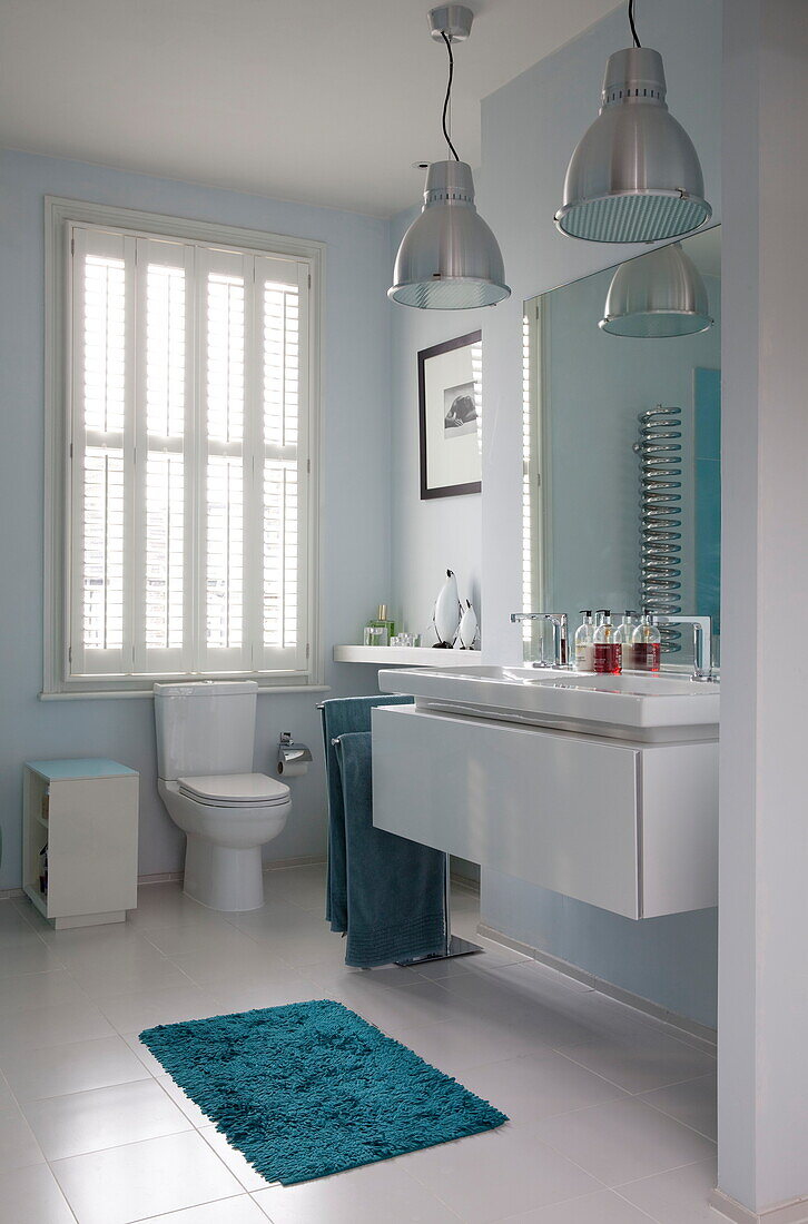 Türkisfarbene Badematte und verchromte Pendelleuchten im Badezimmer eines Stadthauses in London, England, UK