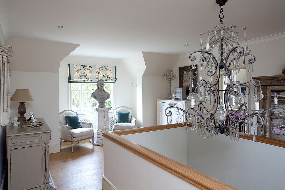 Cut glass chandelier above stairwell with seating in Kent home, England, UK