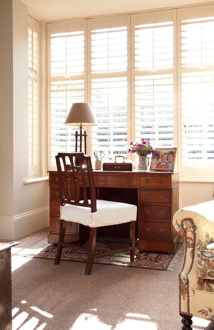 Antique wooden desk and chair at sunlit window of Kent home England UK