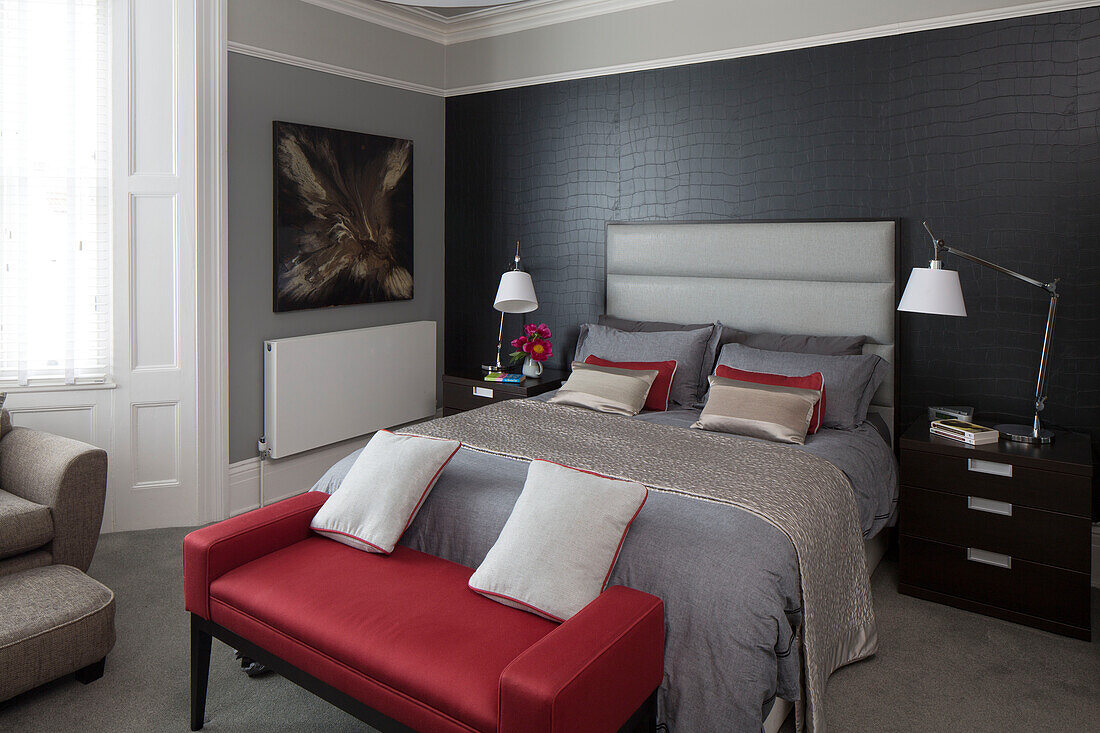 Red seat at foot of grey double bed in contemporary Brighton home, East Sussex, England, UK