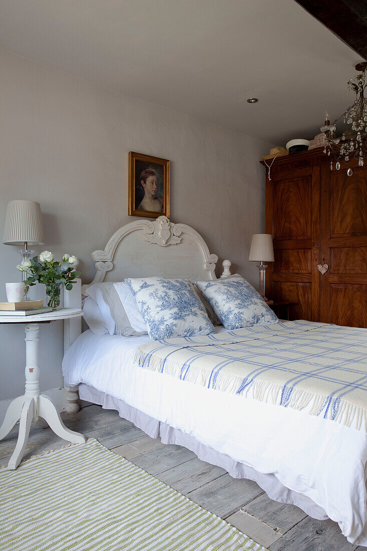 Toile de jouy cushions and checked cover on bed with cut roses at beside in West Sussex home, England, UK