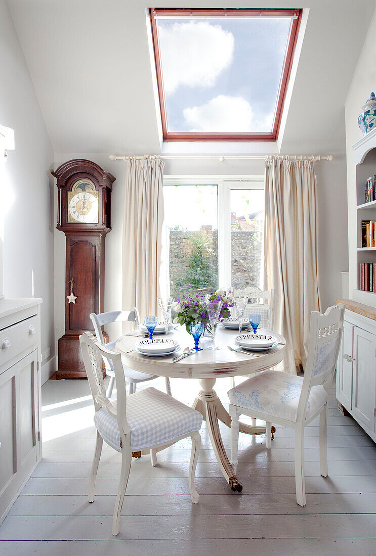 Grandfather clock and dining table below skylight in West Sussex home, England, UK