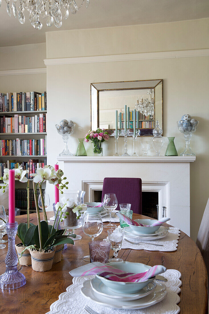 Wooden dining table with fireplace and bookshelf in London home England UK