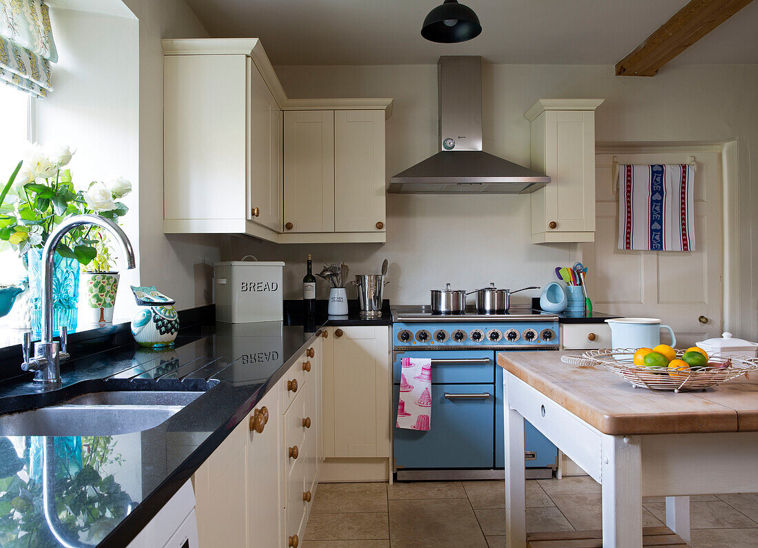 Saucepans on light blue range oven in cream fitted kitchen in London home England UK