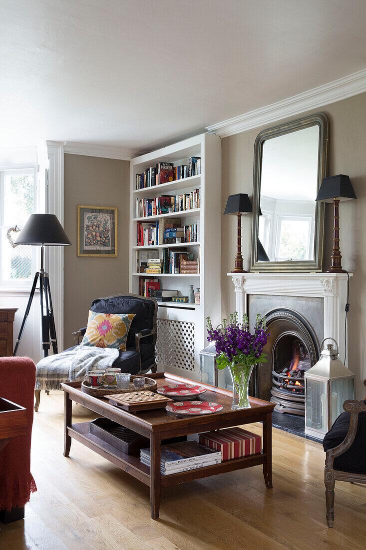 Wooden coffee table in front of lit fire in London home, England, UK