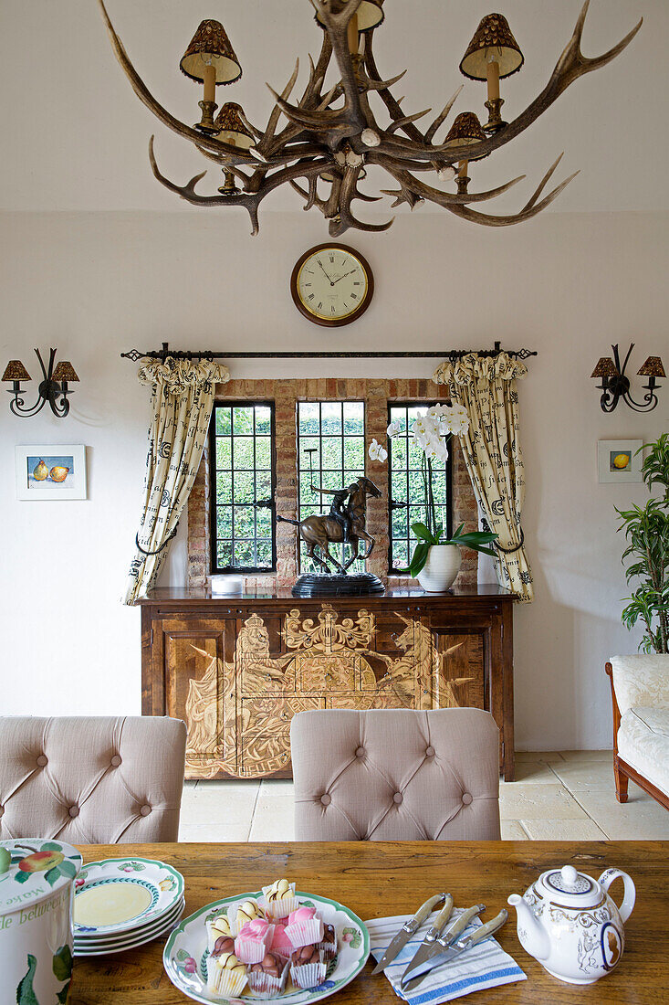 Teekanne und Teller auf einem Esstisch mit einer Reiterstatue auf einem Sideboard in einem Londoner Haus, UK