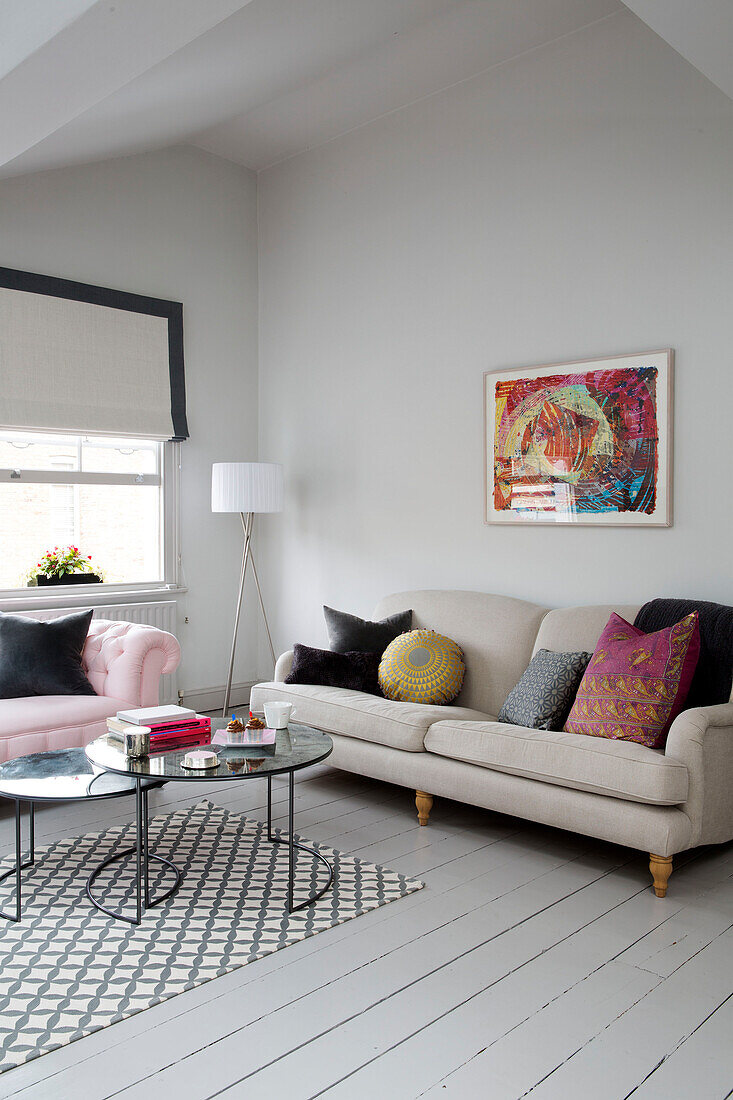 Modern artwork above cream sofa in living room with painted floorboards in Georgian London townhouse England UK