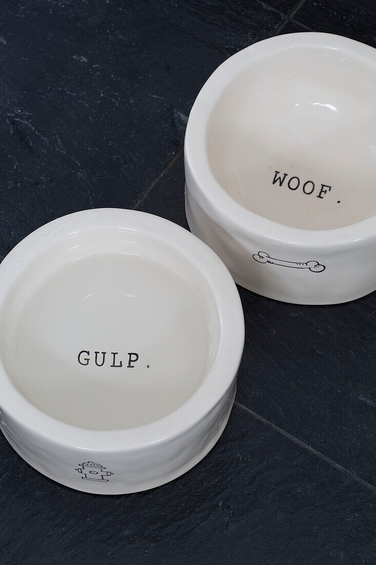 "Zwei weiße Hundenäpfe mit den Worten GULP"" und ""WOOF"" in einem Londoner Stadthaus, England, UK"""