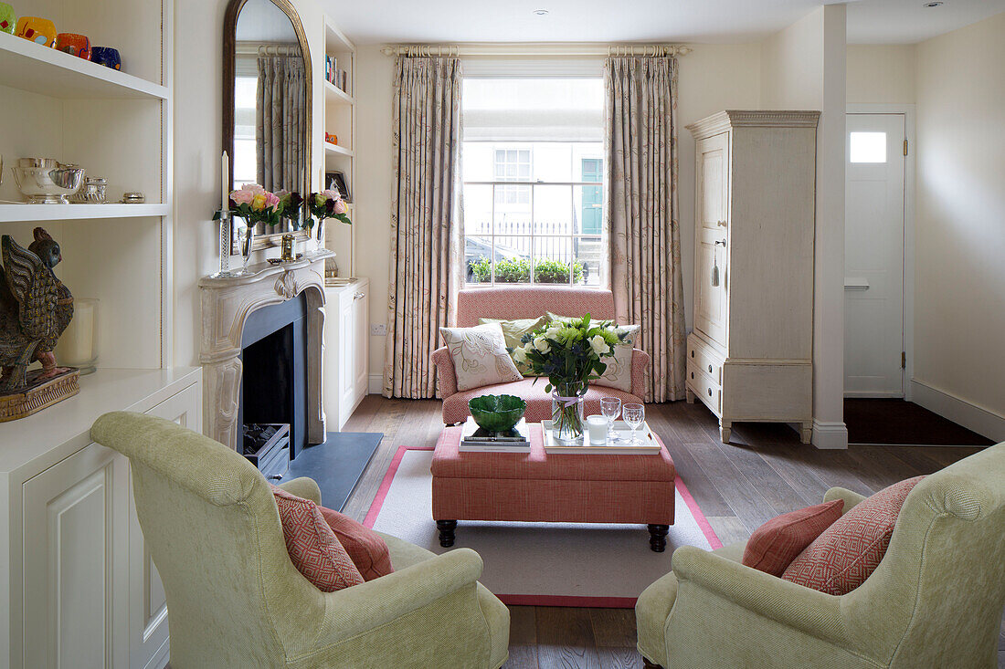 Geschnittene Rosen auf rosa Ottomane im Wohnzimmer mit Sprossenfenster in Londoner Stadthaus, England, UK