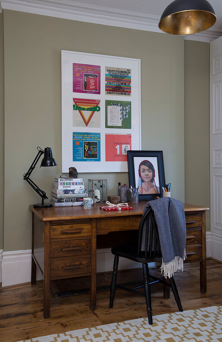Wooden desk with painted black chair and framed artwork in London home, England, UK