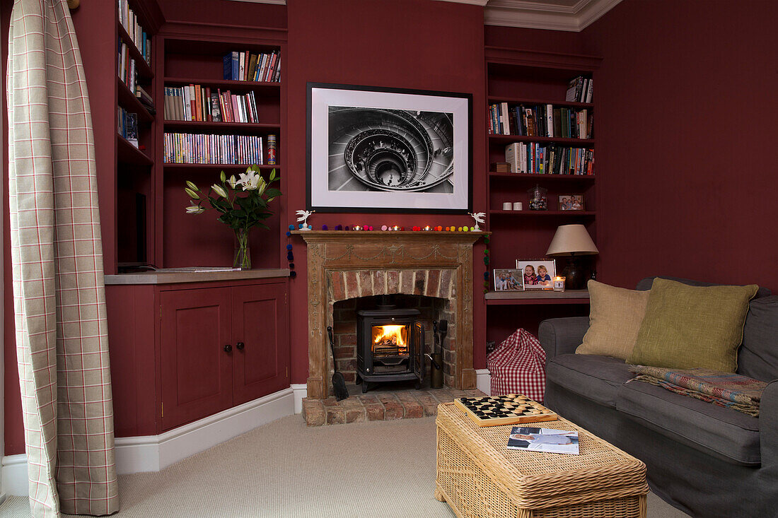 Grey sofa at lit fireside in living room with recessed shelving in Shoreham by Sea home   West Susses   England   UK