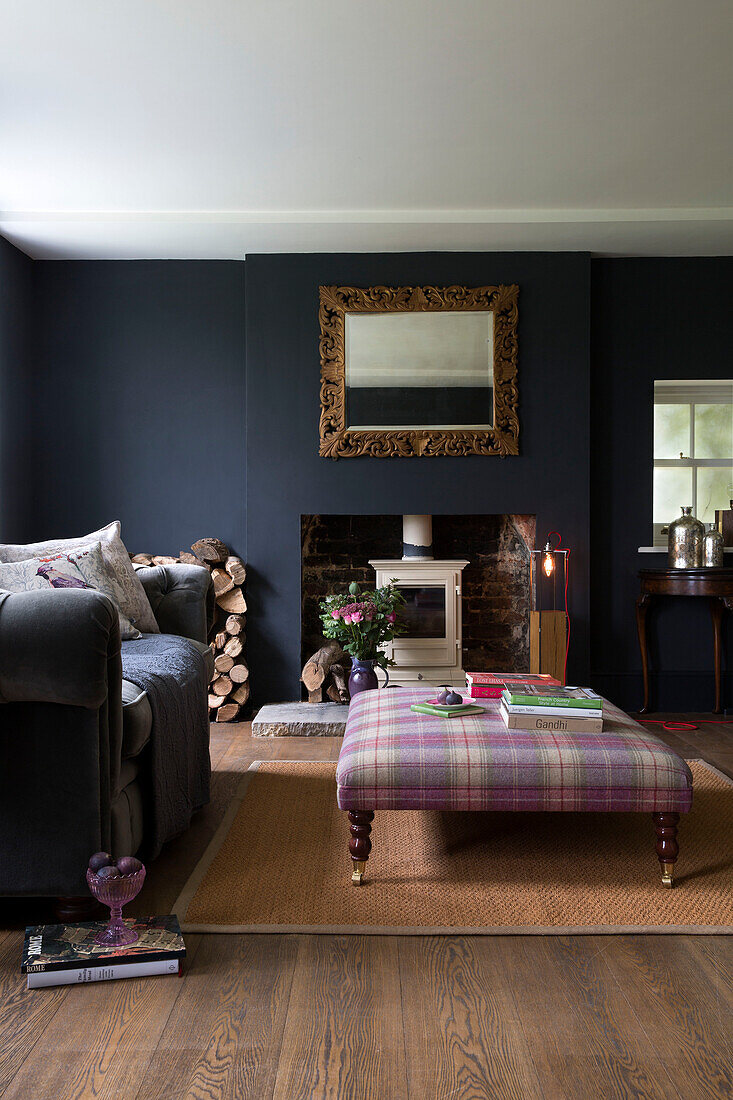 Tartan Ottomane mit grauem Sofa und geschnitztem Holzspiegel im Wohnzimmer in Sussex UK