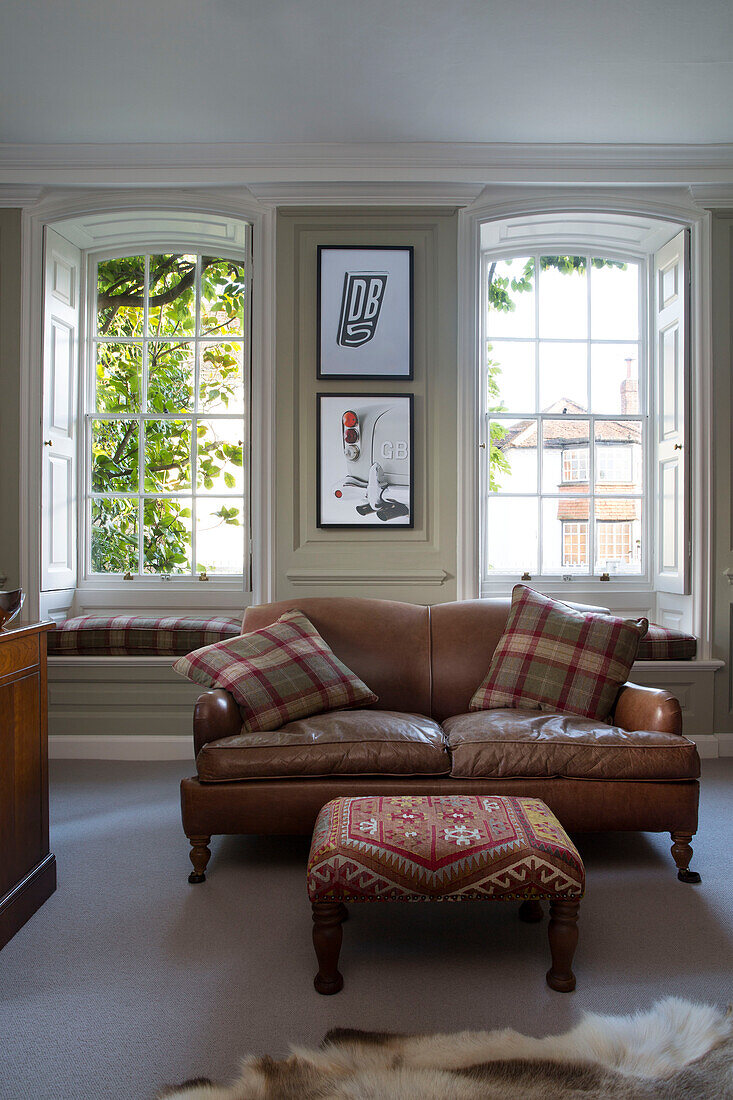 Tartan-Kissen auf braunem Zweisitzer-Sofa aus Leder in einem Haus in Surrey, England, UK
