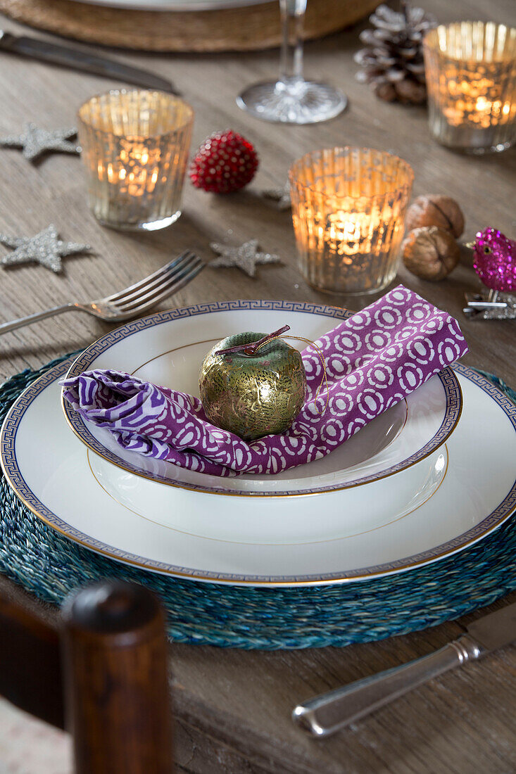 Gold apple on place setting with lit candles in King's Lynn dining room  Norfolk  England  UK